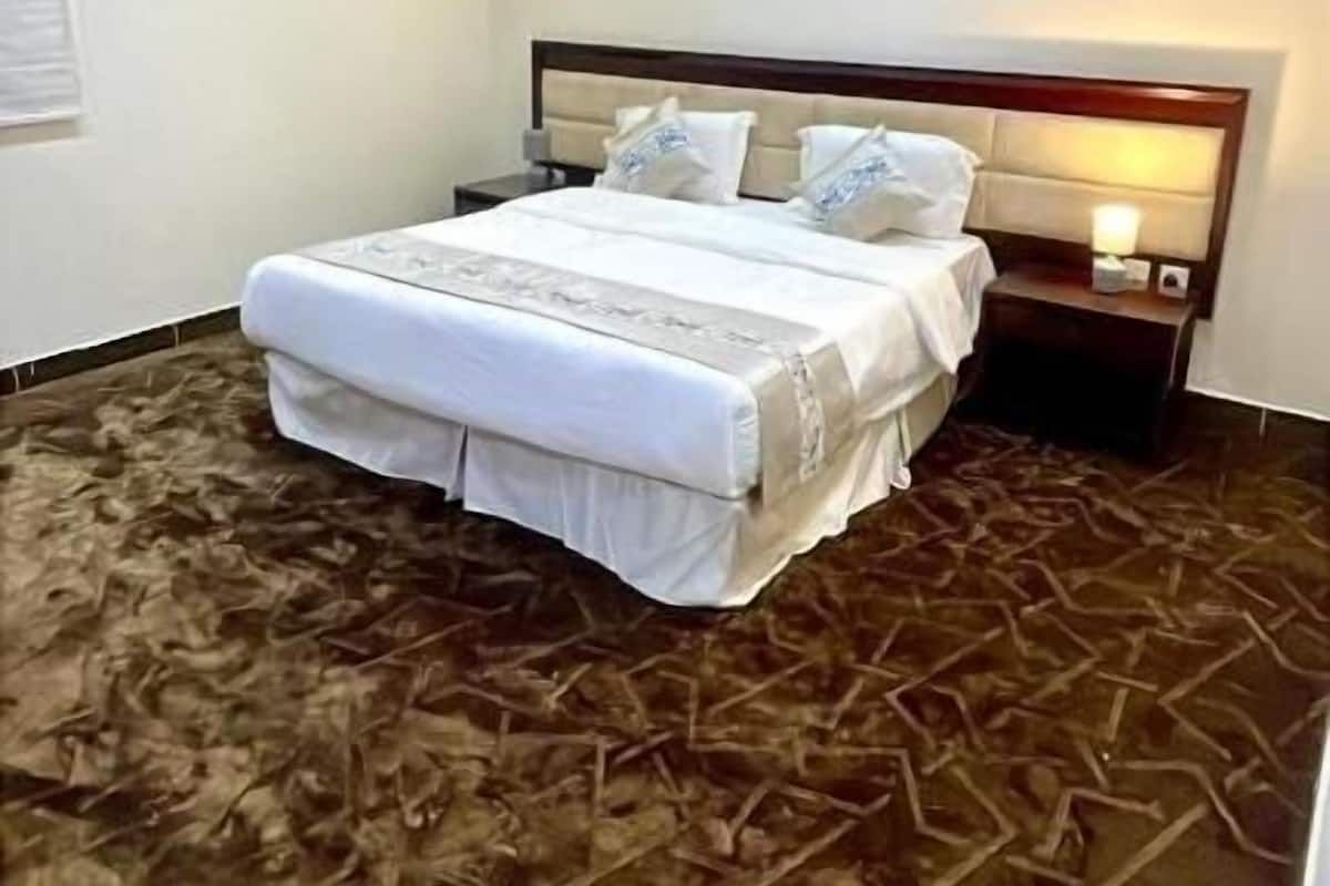 Un dormitorio con cama, mesitas de noche y una lámpara fijada a la pared.