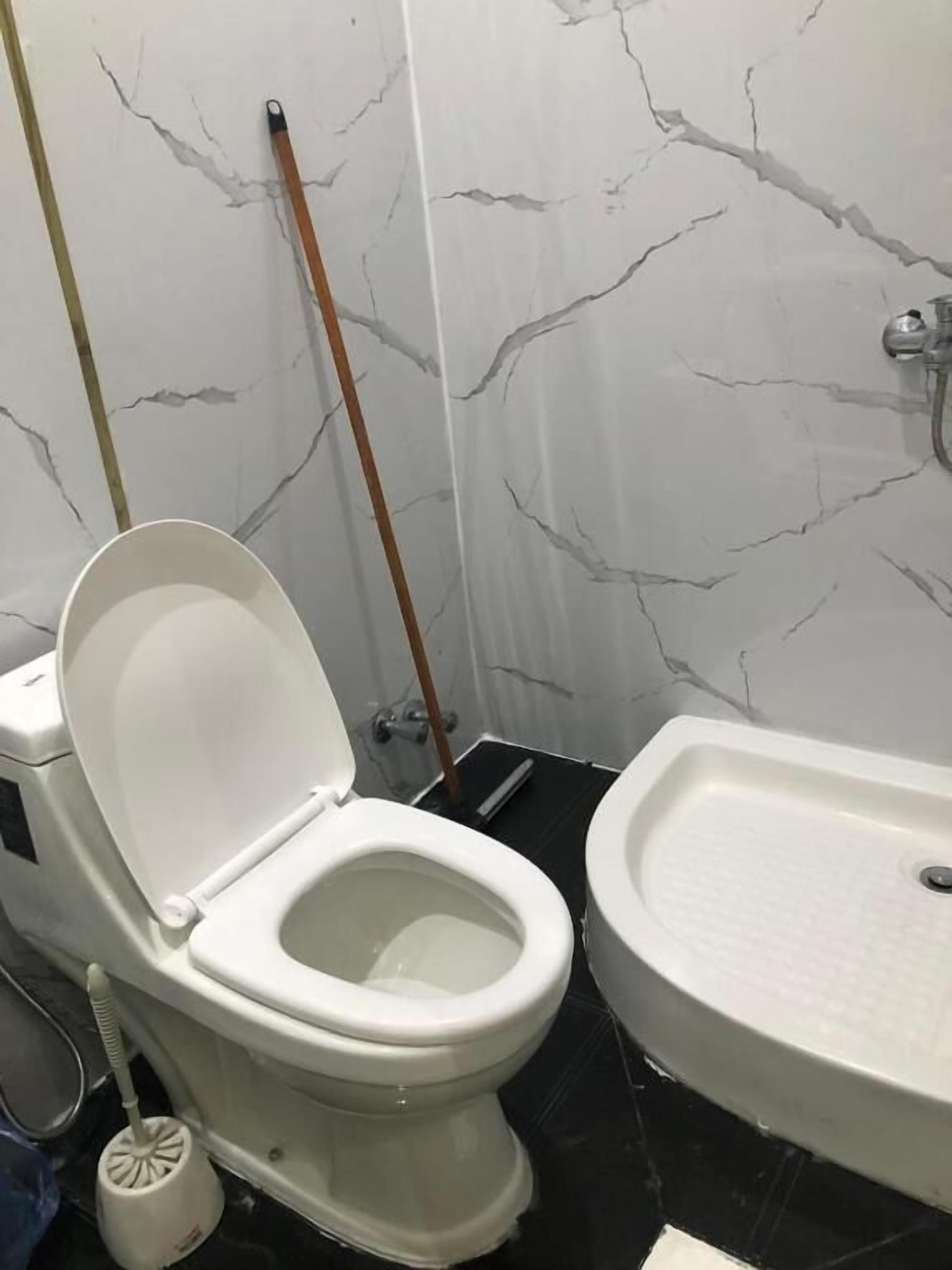 A bathroom with a toilet, a bidet, a mop, and a sink.