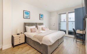 Une chambre à coucher avec un lit, des tables de chevet, un bureau et une chaise.
