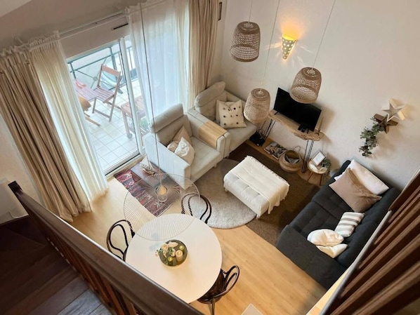 Ein modernes Wohnzimmer mit Sofa, Sessel und Esstisch.
