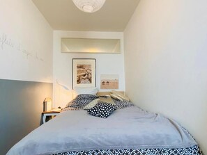 Ein Schlafzimmer mit einem Bett, einem Nachttisch, einer Lampe und zwei gerahmten Bildern an der Wand.