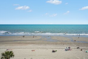 Ein Strand mit Menschen, wolkenlosem Himmel und ruhigem Wasser.