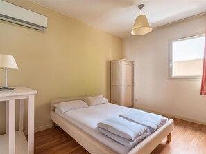 A bedroom with a bed, a bedside table with a lamp, a wardrobe, and a window. - Coastal Couples Retreat Near Argentiere (La Londe-les-Maures)