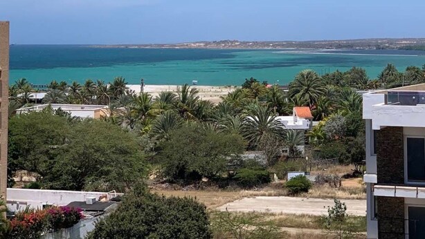 A coastal view with a clear sky, a beach, and residential buildings.