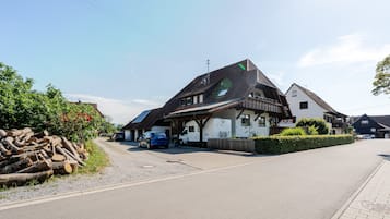 Ein traditionelles Gebäude im europäischen Stil mit Satteldach, einer sichtbaren Garage und einem gepflasterten Einfahrt.