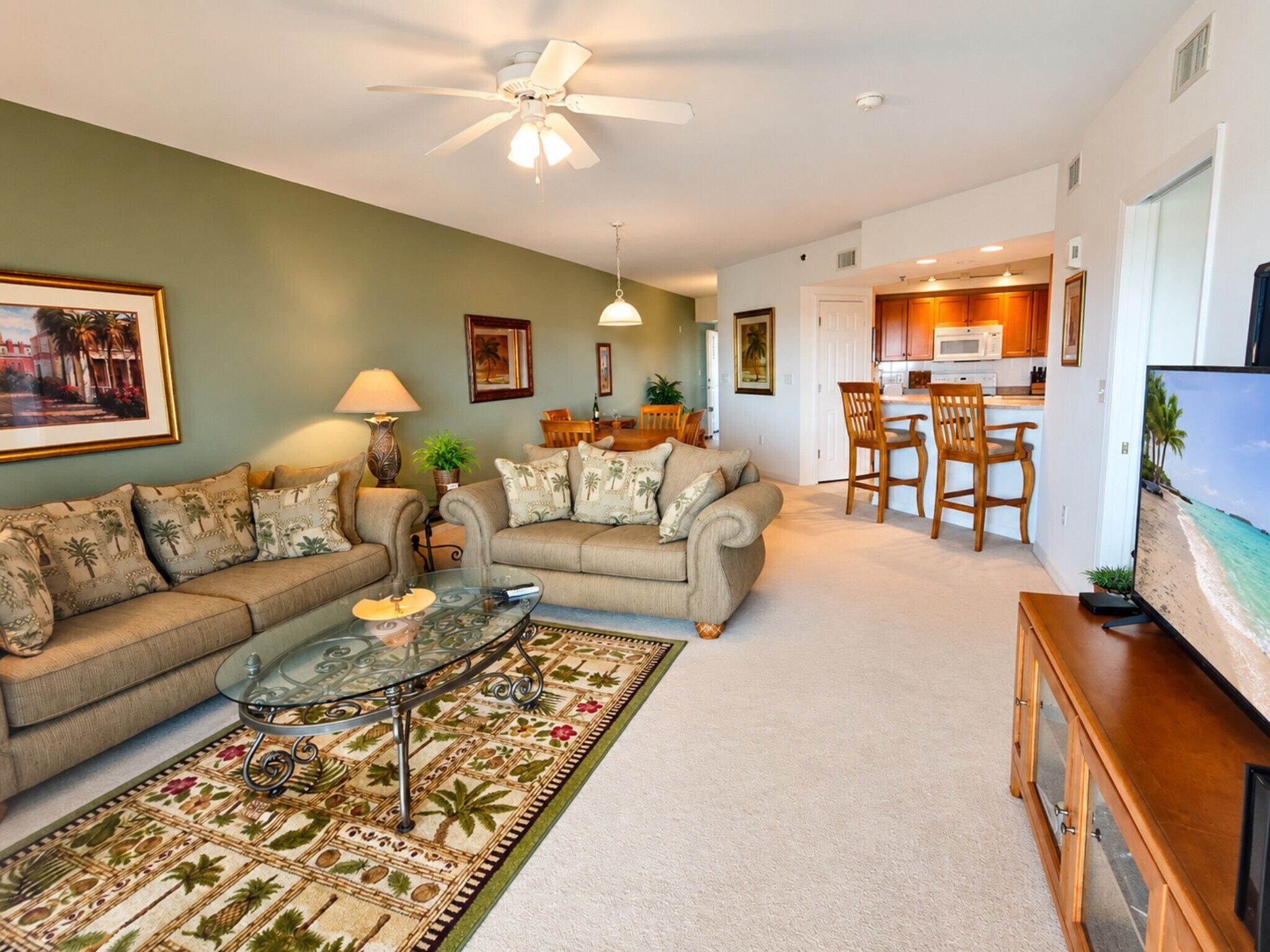 A living room with a sofa, coffee table, and TV, a dining area with chairs, and a kitchen in the background.