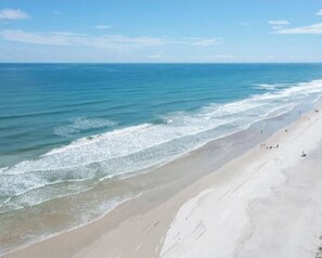 A beach with a wide sandy shore and gentle waves. - New Smyrna Beach • Ocean 2BR Condo • Steps to Sand
Pools, Amenities +Ocean Walk (New Smyrna Beach)