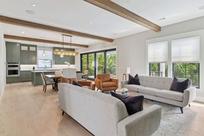 Ein modernes Wohnzimmer mit einer Couch, Sesseln und einem Essbereich mit Tisch und Stühlen.