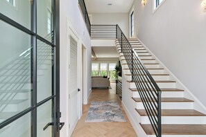 Ein modernes Interieur mit Treppe, Glastüren und Holzboden.