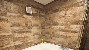 A corner bathroom with a freestanding bathtub, a shower, and a ventilation vent. - Cozy 1-bedroom apartment with AC and a jetted tub in gorgeous Strasbourg (Strasbourg)