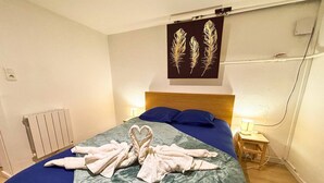 A hotel room with a bed, two bedside lamps, a radiator, and a wall-mounted artwork. - Cozy 1-bedroom apartment with AC and a jetted tub in gorgeous Strasbourg (Strasbourg)