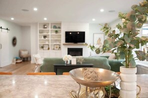 A modern living room with a sofa, a coffee table, and a television. - Casa Bonita PEI – Spacious, Relaxing, Dog-Friendly (Stratford)