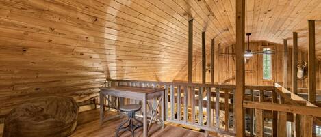 A wooden interior with a table and bench, a wooden railing, and a mounted animal head.