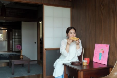 A room with a traditional Japanese sliding door, a wooden table with a vase, and a painting on a desk.