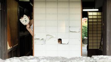 A traditional Japanese room with tatami flooring, a shoji screen, and a wooden door.