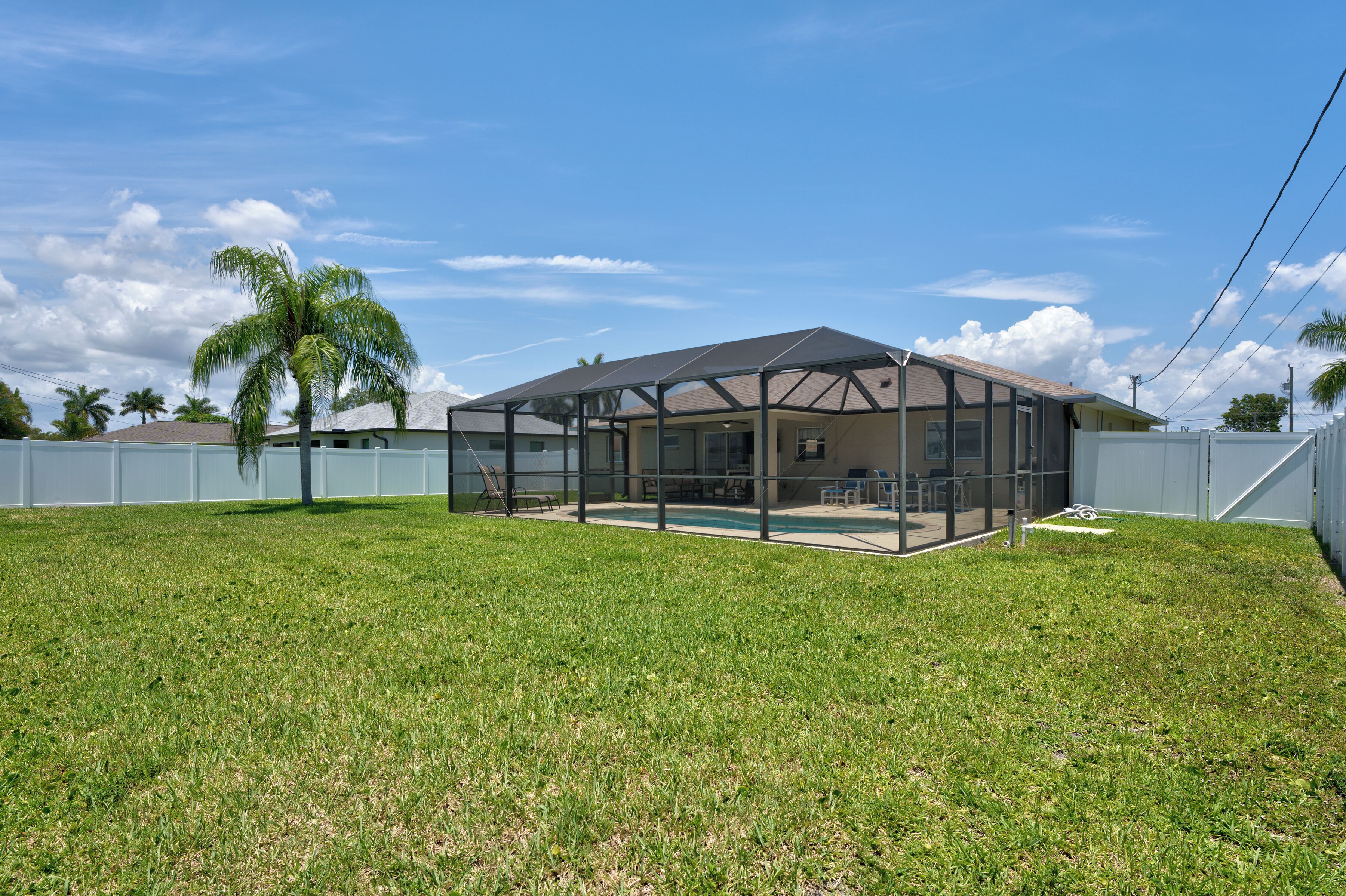 A house with a covered patio, a swimming pool, and a fenced yard.
