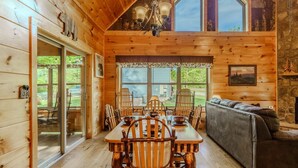 A wooden cabin interior with a dining table, chairs, a sofa, and a fireplace. - Gatlinburg-2brs-hot Tub-arcade Games-fireplace (Gatlinburg)