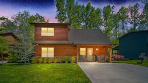 A two-story house with a stone foundation, a wooden exterior, and a driveway leading to the entrance. - Gatlinburg-2brs-hot Tub-arcade Games-fireplace (Gatlinburg)