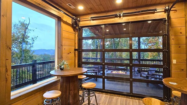 Un interior de madera con ventanas amplias, un balcón y mobiliario para exteriores.