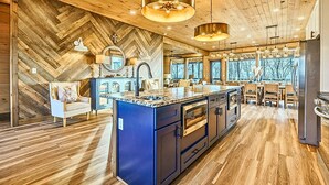 Una cocina moderna con una isla grande, suelo de madera e iluminación colgante.