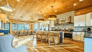 Una cocina moderna con pisos de madera, iluminación colgante y una isla central con taburetes.