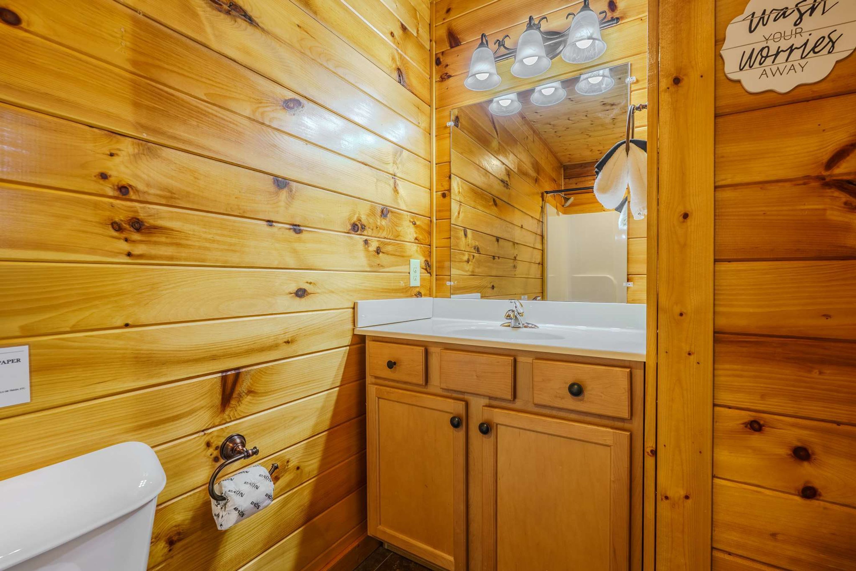 A wooden cabin bathroom with a white sink, mirror, and wooden cabinets.