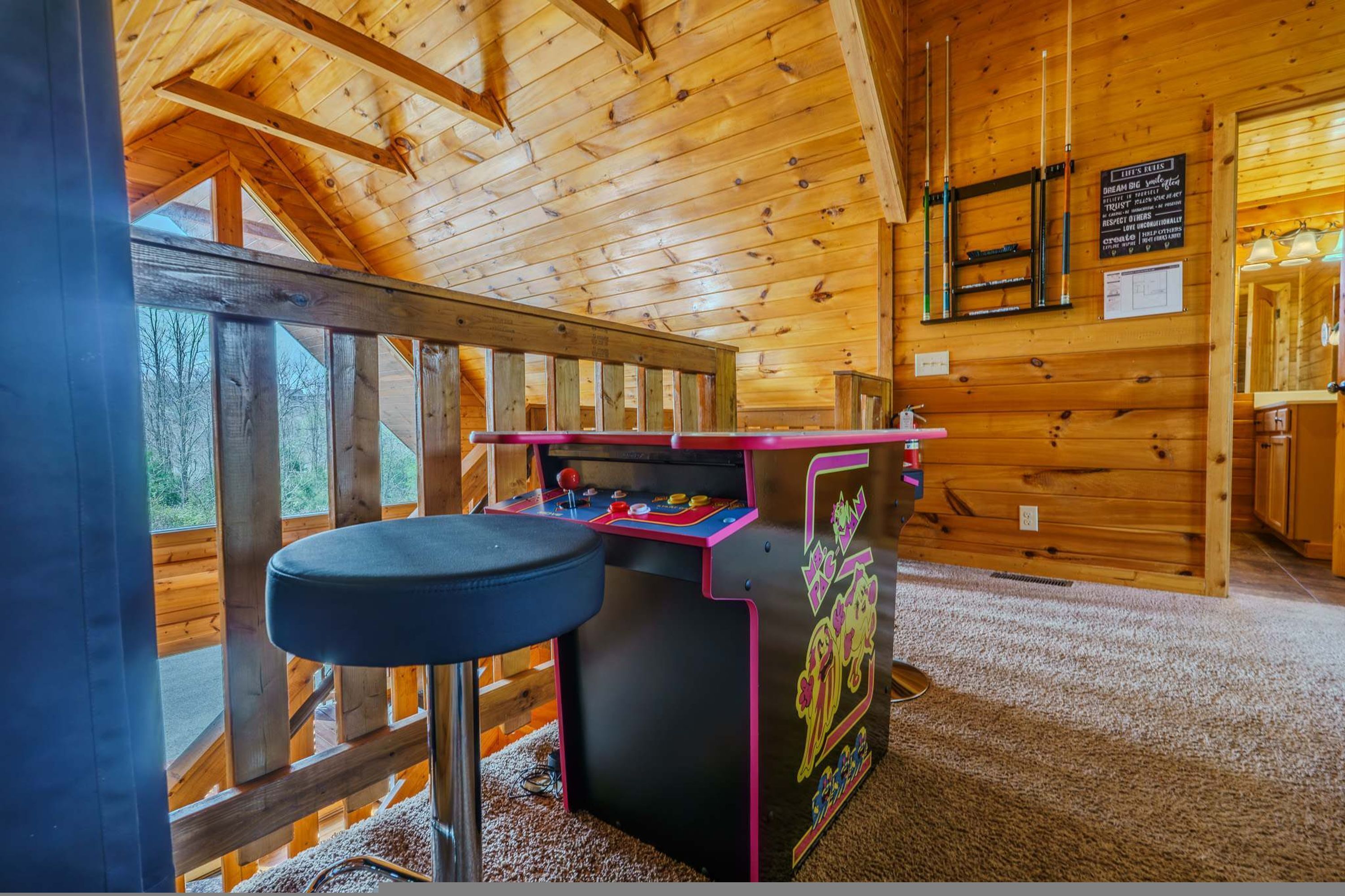 A wooden interior with a pool table, a wooden deck outside, and a sign on the wall.