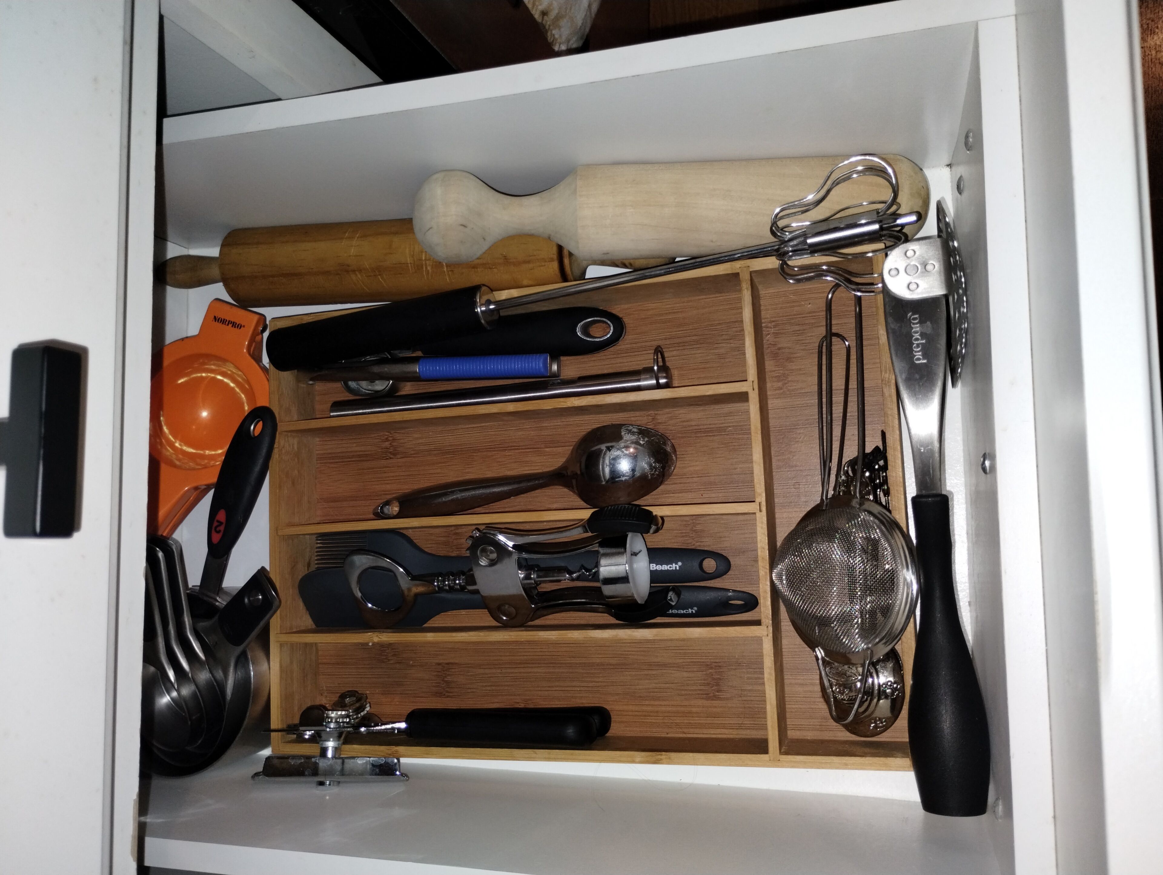 A kitchen drawer with various utensils and tools.