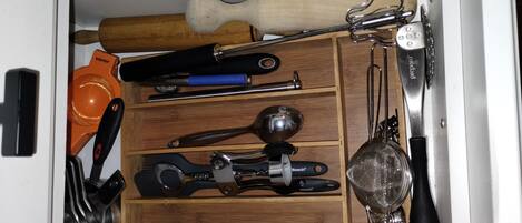 A kitchen drawer with various utensils and tools.