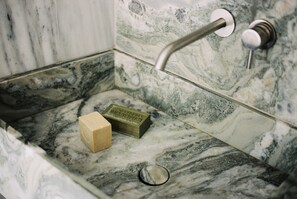 Une salle de bain avec un lavabo en marbre, un savon et un robinet.