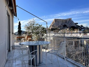 Un balcon avec une table et des chaises, offrant une vue sur un fort historique et le paysage urbain.