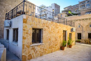 A stone building with a balcony, potted plants, and a courtyard. - NAHIL MİSAFİREVİ MARDİN (ARTUKLU)
