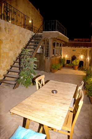 A wooden table with benches, a staircase, and potted plants in an outdoor area. - NAHIL MİSAFİREVİ MARDİN (ARTUKLU)