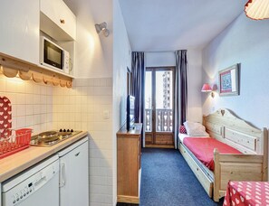 A compact hotel room with a kitchenette, a single bed, a small table, and a balcony with a view. - Compact Alpine Stay for Five (Risoul)