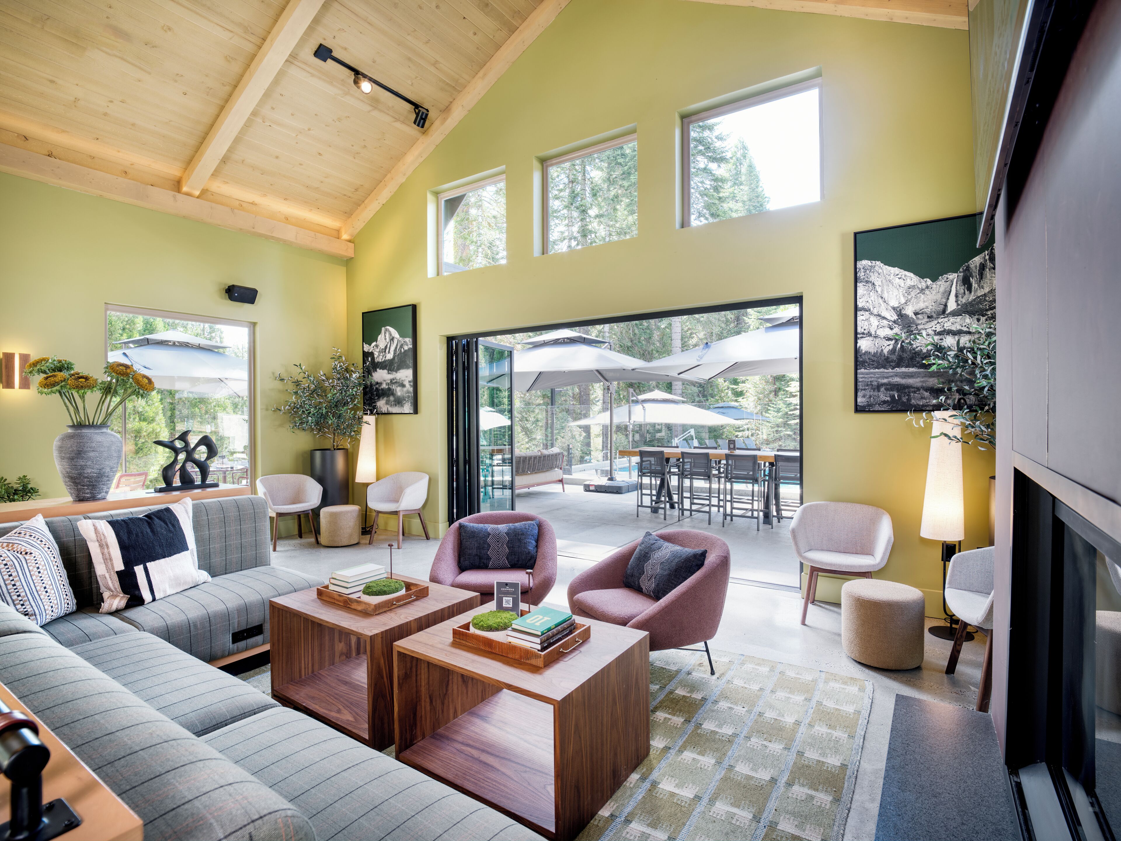 A modern living room with a sofa, armchairs, a coffee table, and a dining area with outdoor umbrellas.