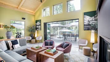 A modern living room with a sofa, armchairs, a coffee table, and a dining area with outdoor umbrellas.