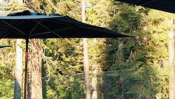 An outdoor seating area with a sofa and two chairs, a table, and two umbrellas.