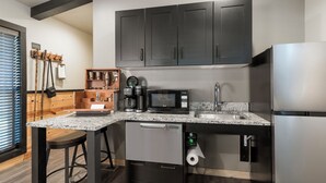 Una cocina moderna con armarios oscuros, un refrigerador de acero inoxidable, una cafetera y un microondas.