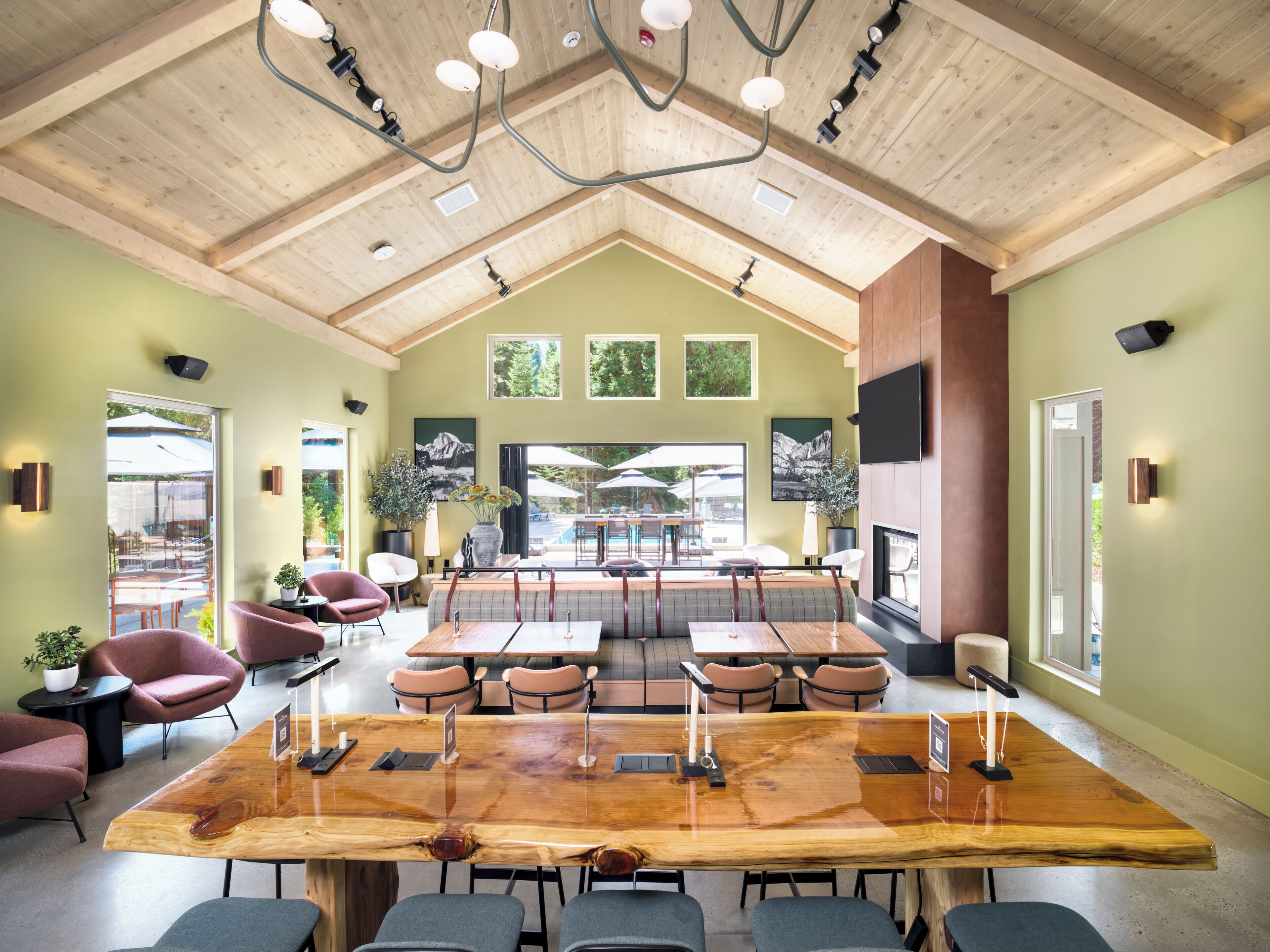 A spacious room with a large wooden table, multiple seating options, and a high ceiling with exposed beams.