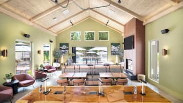 A spacious room with a large wooden table, multiple seating options, and a high ceiling with exposed beams.