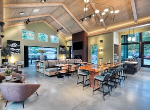 A spacious indoor area with a long wooden bar, seating arrangements, and large windows allowing natural light. - Waybound Yosemite (Fish Camp)