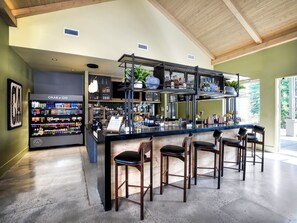 Espaço de bar com balcão, banquetes e prateleiras repletas de garrafas.