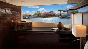 Cozinha com vista para a orla, armários de madeira, cesta, vaso e luminária.