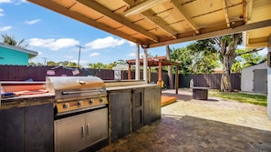 Ein Außenbereich mit Grill, einer Pergola und einer gepflasterten Terrasse.