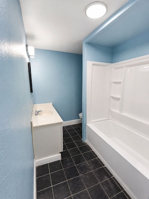 A bathroom with a white sink, a bathtub, and a toilet.
