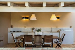 A kitchen with a dining table, chairs, pendant lights, and a backsplash. - Infinity pool villa amongst citrus groves in Noto (Noto)