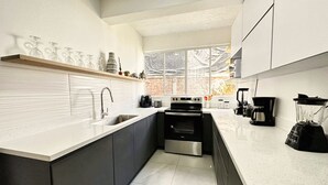 Een moderne keuken met een inbouwoven, een koffiezetapparaat en een blender op het aanrecht.