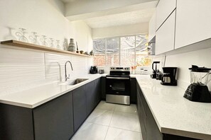 Eine moderne Küche mit eingebautem Ofen, einer Kaffeemaschine und einem Mixer auf der Arbeitsplatte.