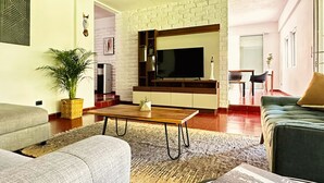 Een woonkamer met een bank, een salontafel, een televisie en een bakstenen muur.