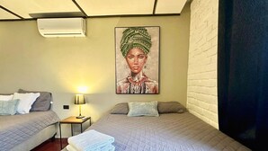 Een hotelkamer met twee bedden, een schilderij aan de muur, een lamp en een opgevouwen handdoek op het bed.